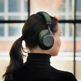 Person set bagfra med grønne sackit Touch 410 over-ear høretelefoner på hovedet i et lyst moderne rum