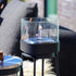 Sort Patio Accessory Stand med SACKit Bio Lamp i rustfrit stål og varmebestandigt glas på bord.