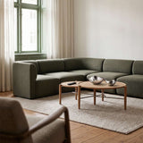 Olivegrøn hjørnesofa fra sackit i en lys stue med rundt sofabord og bløde tekstiler i skandinavisk stil