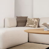 Lys cremefarvet hjørnesofa fra sackit med bløde afrundede former og dekorative puder ved et rundt sofabord i en rolig skandinavisk stue