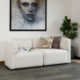 Lys beige Fjord sofa fra sackit med bløde afrundede former og pyntepuder i en stilren nordisk stue med kunst på væggen og grøn plante