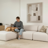 Lys Fjord sofa fra sackit med en kvinde og en hund i en rolig skandinavisk stue med abstrakt kunst på væggen
