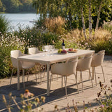 Kirra Dining Table i taupe keramik med seks Kirra Patio stole i en solskinsfyldt have.