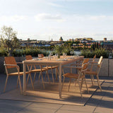 Kirra spisebord med seks komfortable havestole i teak på en solrig terrasse med udsigt over byens tage og grønne planter