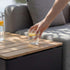 sackit Patio opbevaringsbord i teak med praktisk opbevaring under bordpladen og glas med citron placeret ved siden af en udendørs sofa