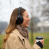 Kvinde med sorte Touch 310 over ear høretelefoner og en kop kaffe på en kold dag udendørsાન્ય