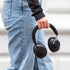 Sorte over ear høretelefoner holdes i hånden af en person iført jeans og sort trøje