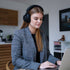 Kvinde iført sorte sackit Touch 400 over ear høretelefoner ved en bærbar computer i et lyst hjemmekontor