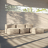Blød beige indendørs sofa med modulopbygning og løse puffer i et lyst rum med store vinduer og naturlige skyggemønstre fra solen