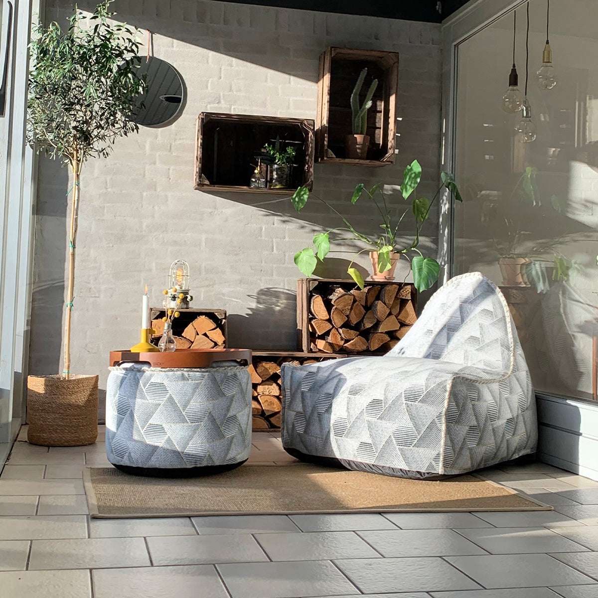 Sort Pouf Noir sækkestol og puf med geometrisk jacquard-tekstil og håndsyede sting på lyst gulv