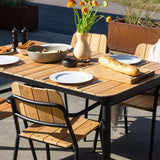 Udendørs spisebord i pulverlakeret aluminium og ubehandlet teaktræ med naturlige variationer i træets farve og struktur.