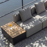 sackit Cobana loungesofa til udendørs brug med grå hynder og træbord med forfriskninger på en solrig terrasse i skandinavisk design