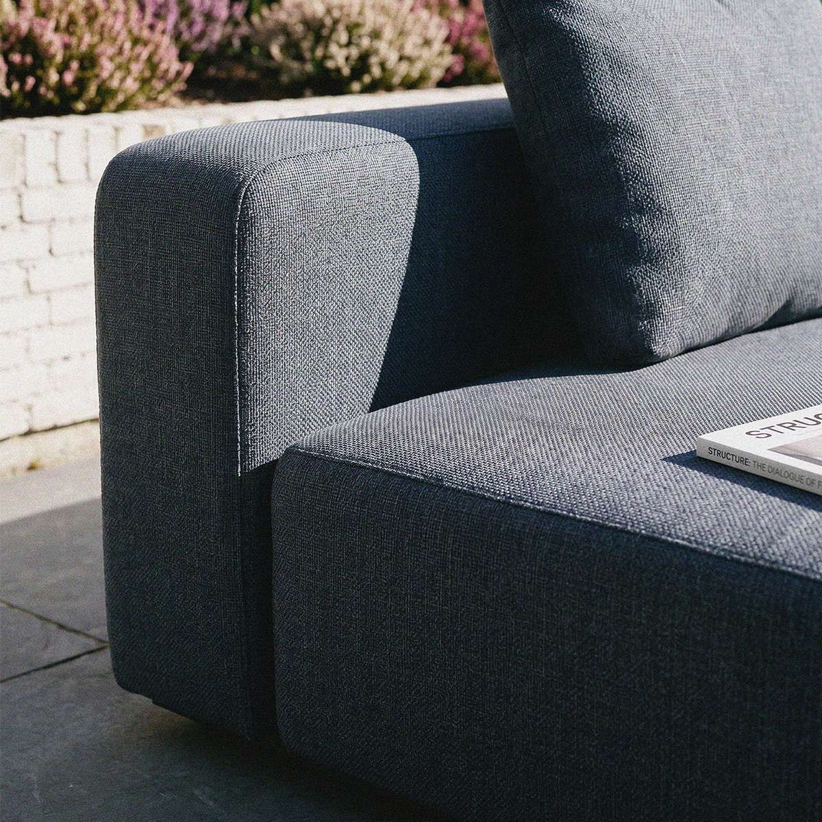 Nærbillede af mørkegrå Cobana loungesofa fra sackit med bløde hynder på en solrig terrasse dansk design til udendørs afslapning