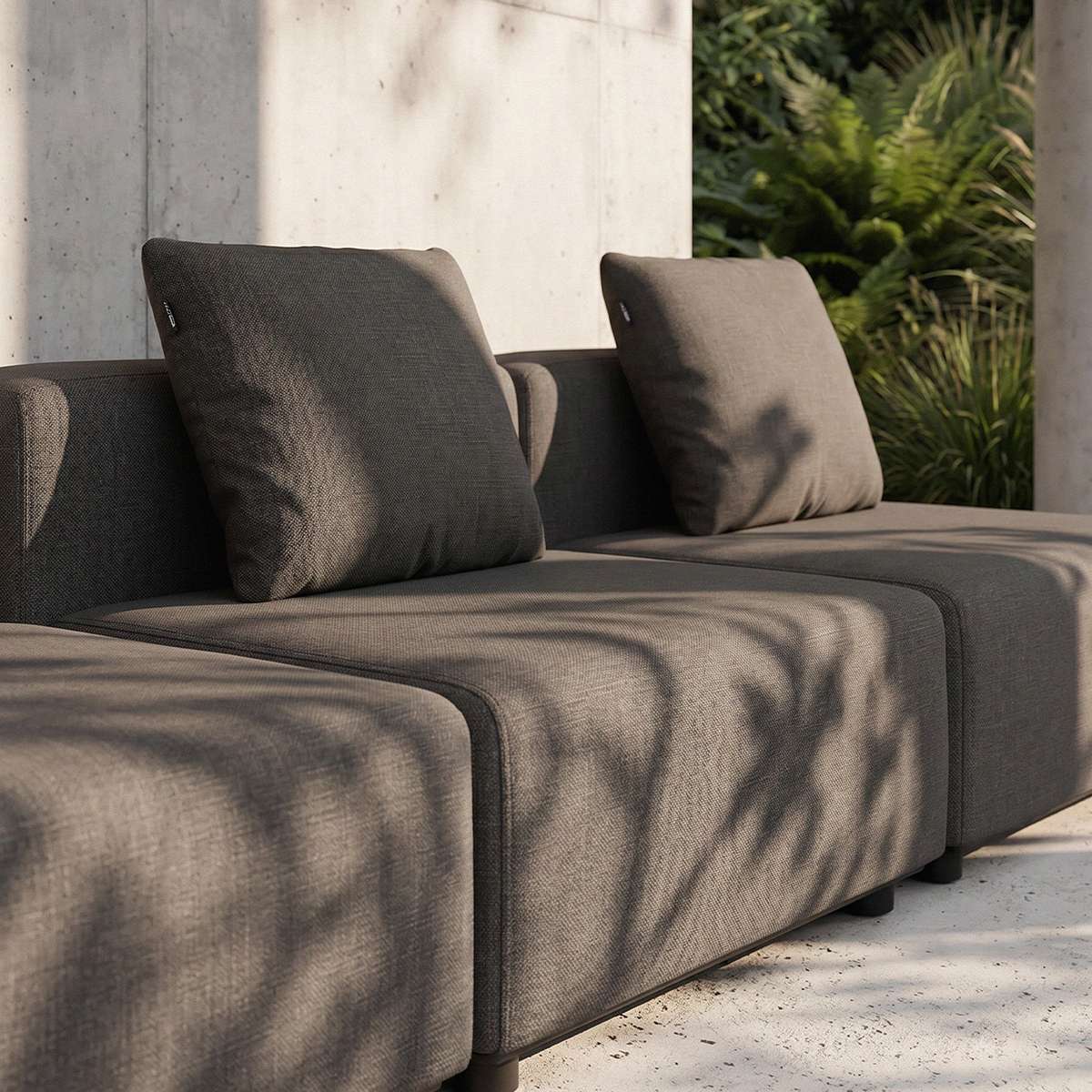 Mørkegrå sackit Cobana loungesofa med bløde ryghynder og rene skandinaviske linjer på en solrig terrasse omgivet af grønne planter