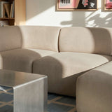 Beige Fjord sofa med højrevendt chaiselong i en lys skandinavisk stue med sofabord bogreol og kunst på væggen