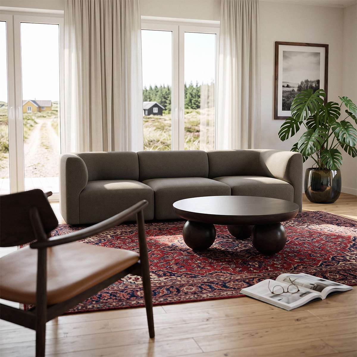 Fjord sofa til tre personer i mørkegråt stof i en lys skandinavisk stue med rundt sofabord mønstret tæppe grøn plante og lænestol
