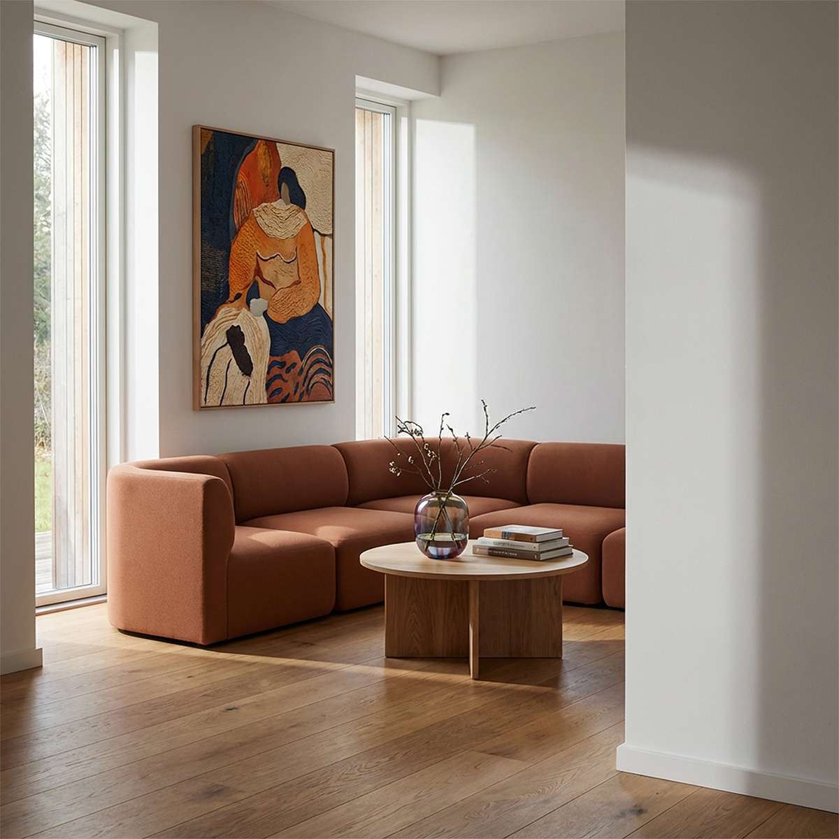 Brun Fjord hjørnesofa fra sackit i en lys skandinavisk stue med kunst på væggen og rundt sofabord i træ