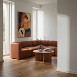 Brun Fjord hjørnesofa fra sackit i en lys skandinavisk stue med kunst på væggen og rundt sofabord i træ