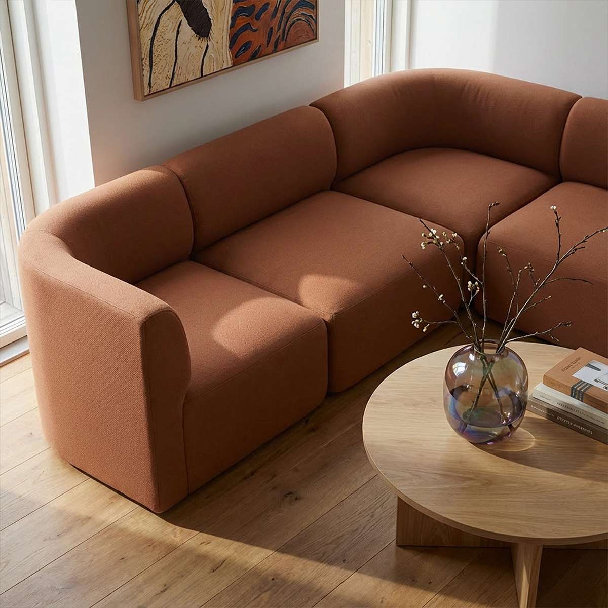 Brun højrevendt Fjord hjørnesofa fra sackit i et lyst nordisk hjem med bløde former træbord og dekorativ vase med grene