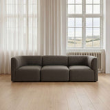 Mørkegrå modulsofa med tre siddepladser i en lys nordisk stue med store vinduer og naturligt dagslys