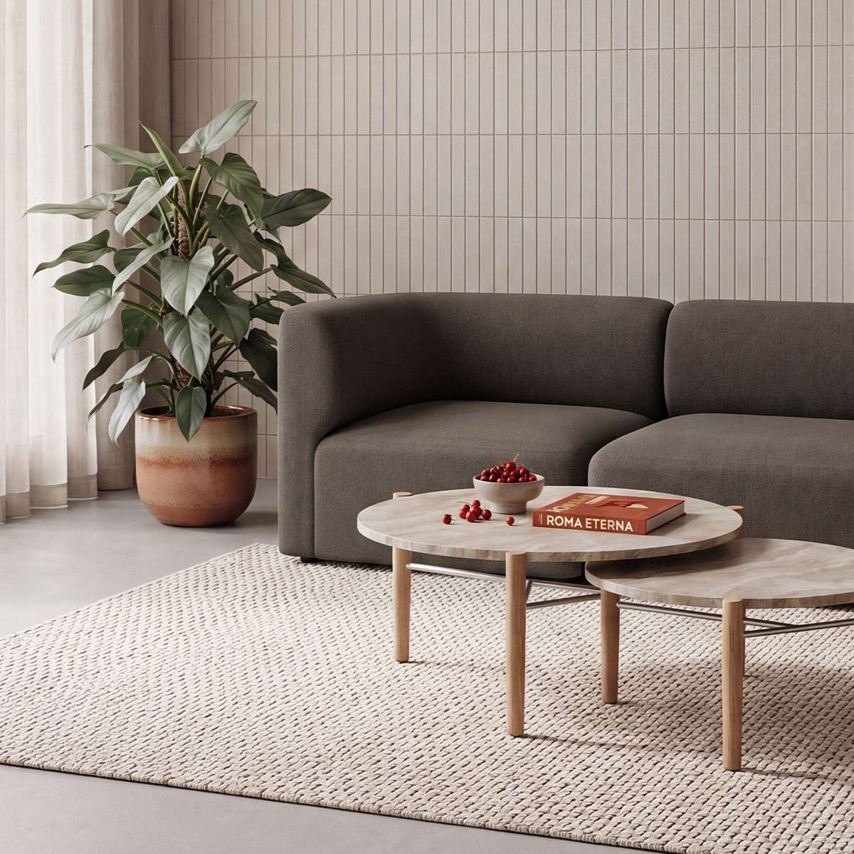 Mørkebrun Fjord Sofa fra sackit i stilren stue med runde sofaborde stor grøn plante og lyst vævet gulvtæppe