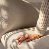 Nærbillede af en hånd på det bløde beige sæde i Fjord Sofa fra sackit med roligt skandinavisk design og behagelig tekstur