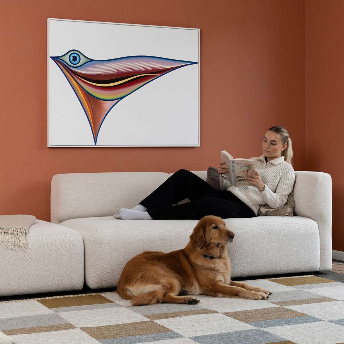 Lys Fjord sofa med åben ende fra sackit i en varm stue hvor en kvinde læser og en hund ligger på gulvet foran sofaen