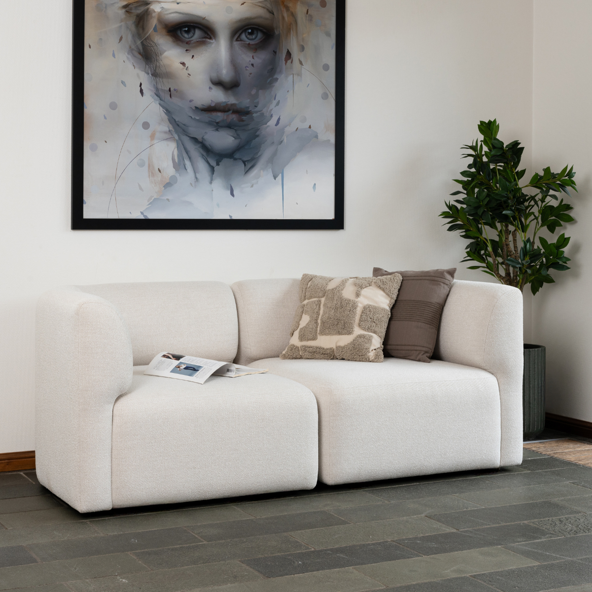 Lys beige Fjord sofa fra sackit med bløde afrundede former og pyntepuder i en stilren nordisk stue med kunst på væggen og grøn plante