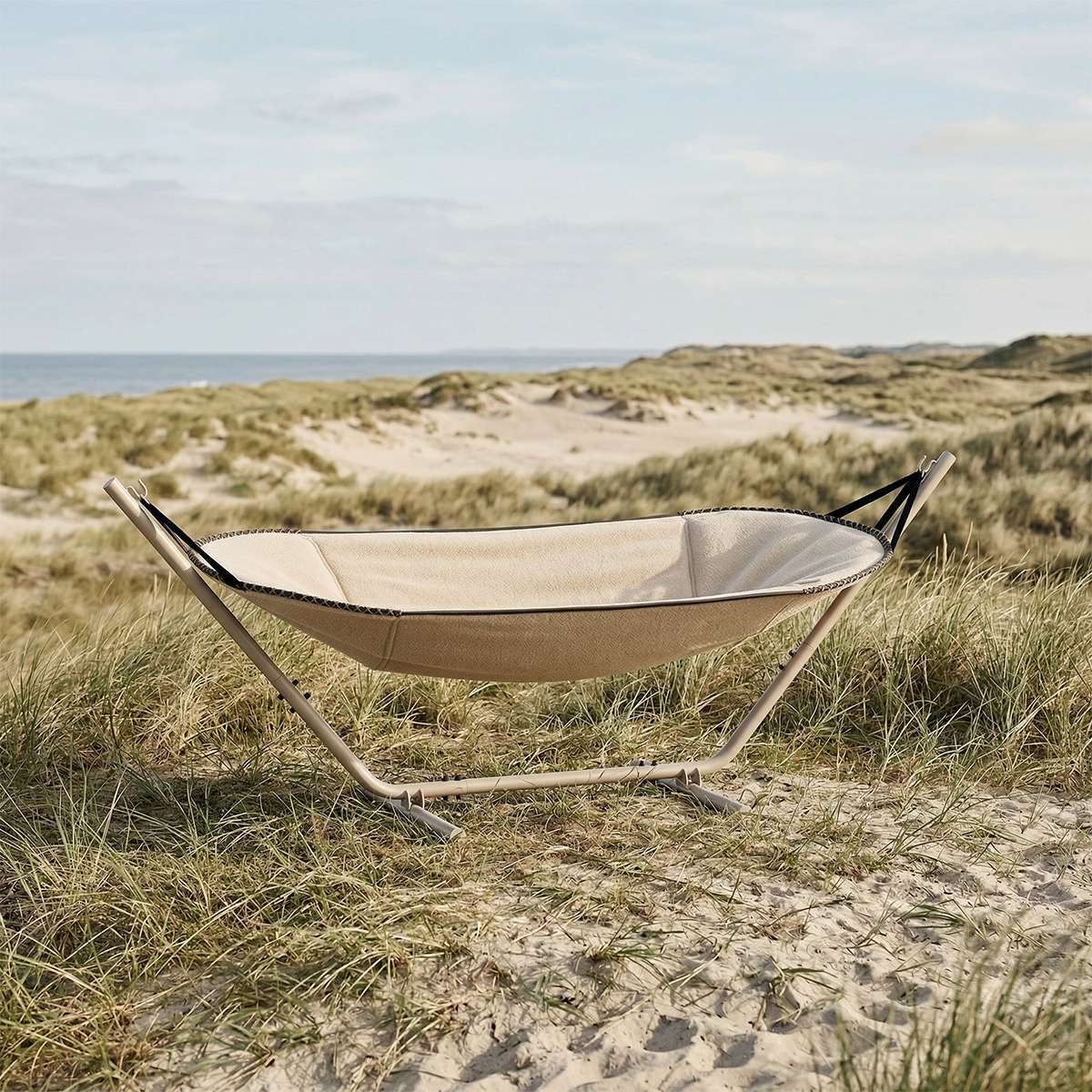 sackit Cobana hængekøje i beige tekstil med stativ placeret i klitterne ved havet og omgivet af marehalm