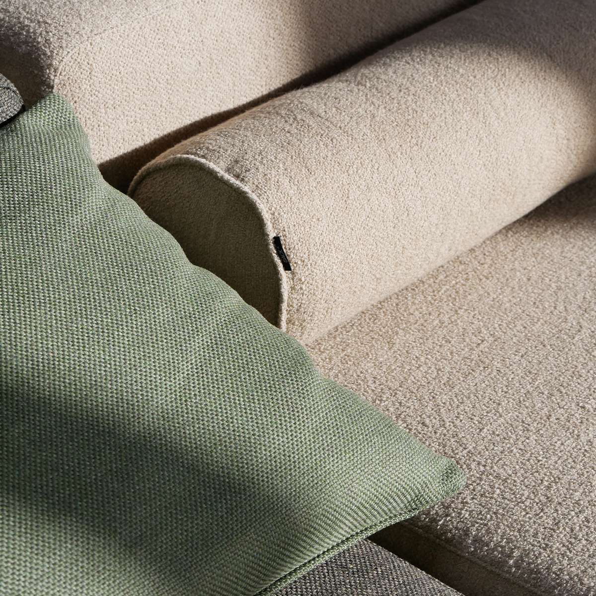 Nærbillede af grøn og sandfarvet tekstil på bløde hynder til en stilren udendørs lounge sofa fra sackit