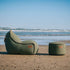 sackit Cobana loungestol og puf i grøn tekstil placeret på en strand ved havet et vejrbestandigt dansk design til udendørs afslapning