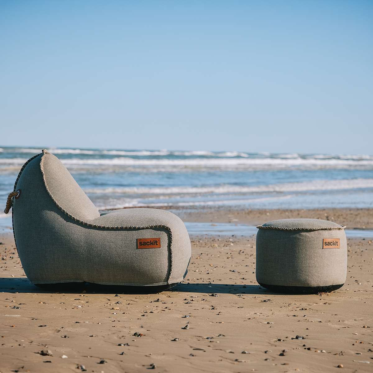 sackit Cobana loungestol og puf placeret på en sandstrand med havet i baggrundenાન્ય