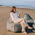 sackit udendørs loungestol og puf på stranden med kvinde der nyder et glas vin i det vejrbestandige design til nordisk vejr