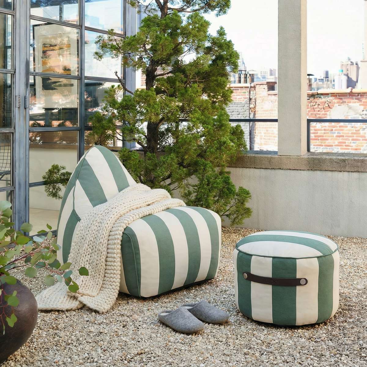 SACKit Chair Outdoor sækkestol i rund form og Renesse Olive farve med sort bund i udendørsmiljø.